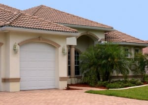 a generic one story florida home with garage, palm trees and a clear blue sky